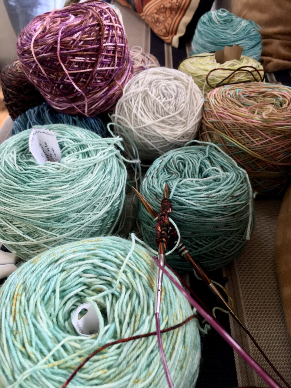 photo of colorful yarn and knitting needles, ready to be knit into a wrap. 